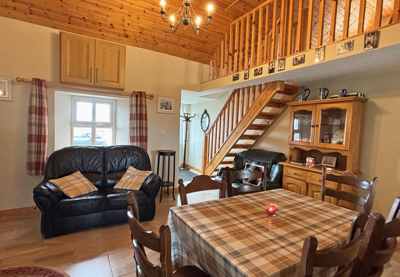 Conroy's Cottage Carna. Dining table, sofa. Cosy room with wooden staircase.